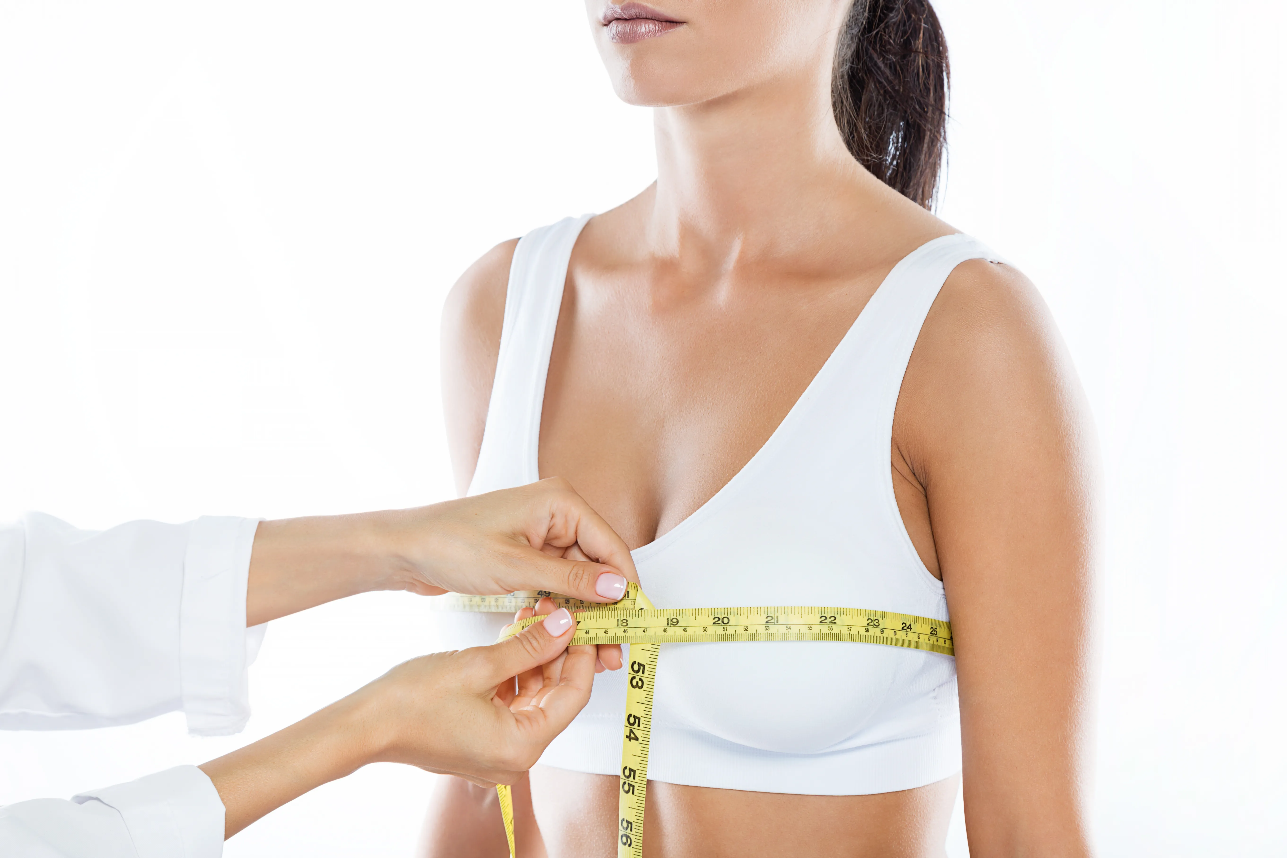 Doctor measuring woman’s chest size before breast enhancement consultation