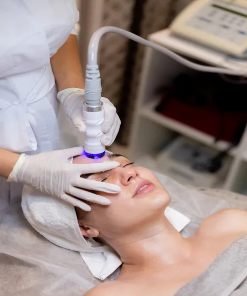 Young woman receiving professional laser facial treatment at aesthetic clinic